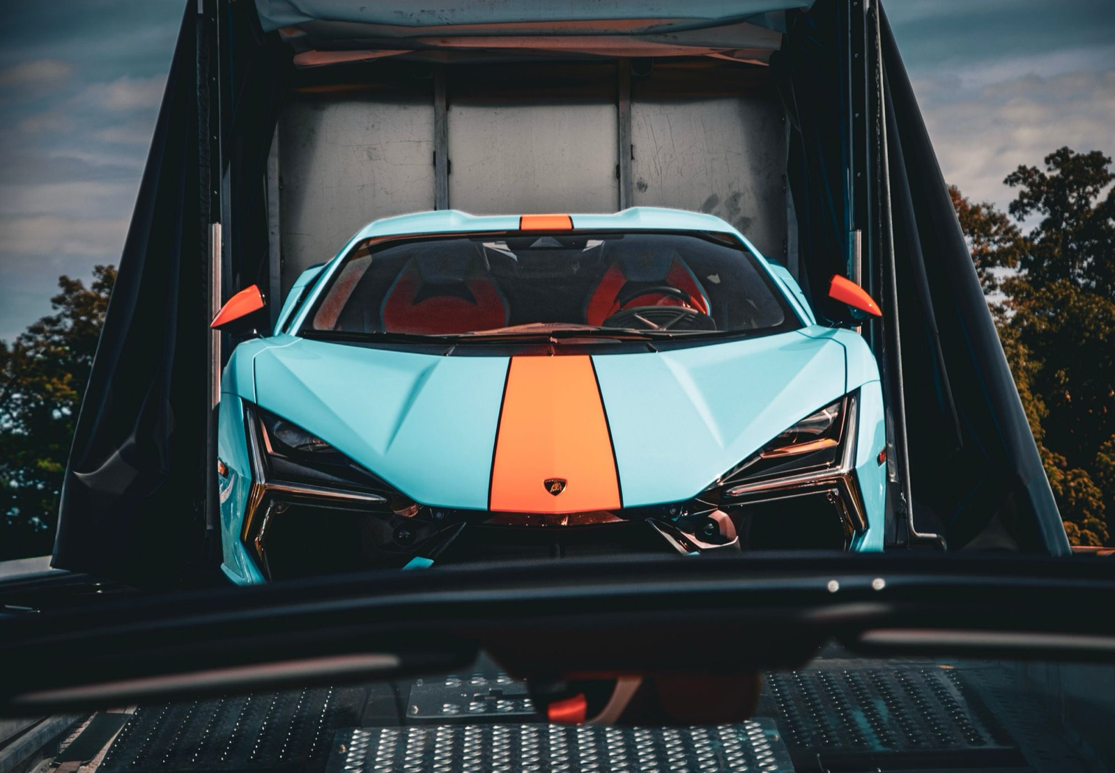 Blue sports car secured inside an enclosed car transport trailer