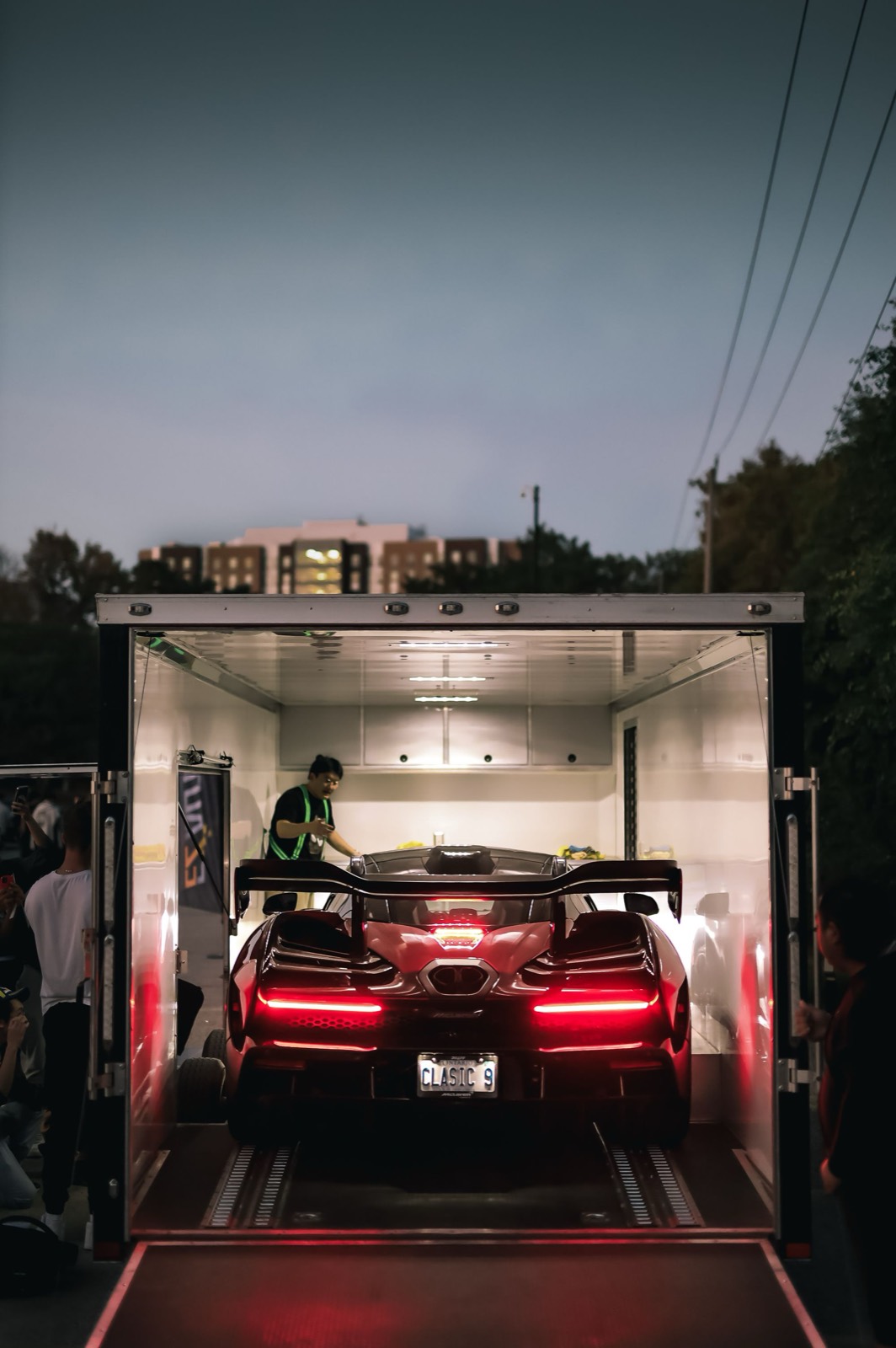 Sports car being loaded into an enclosed trailer at dusk